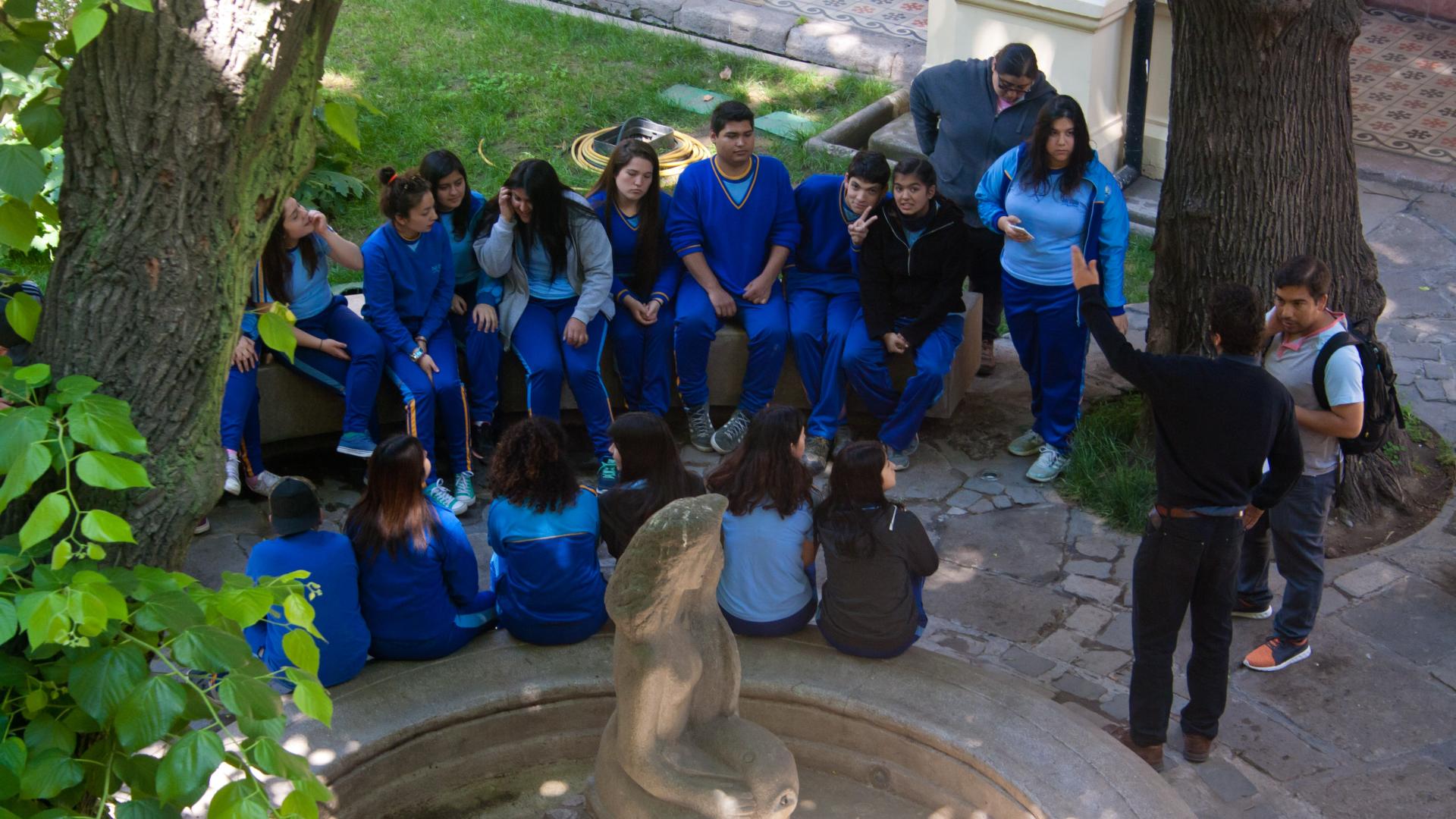 Grupo de estudiantes sentados en la pileta del patio del Museo de la Educación