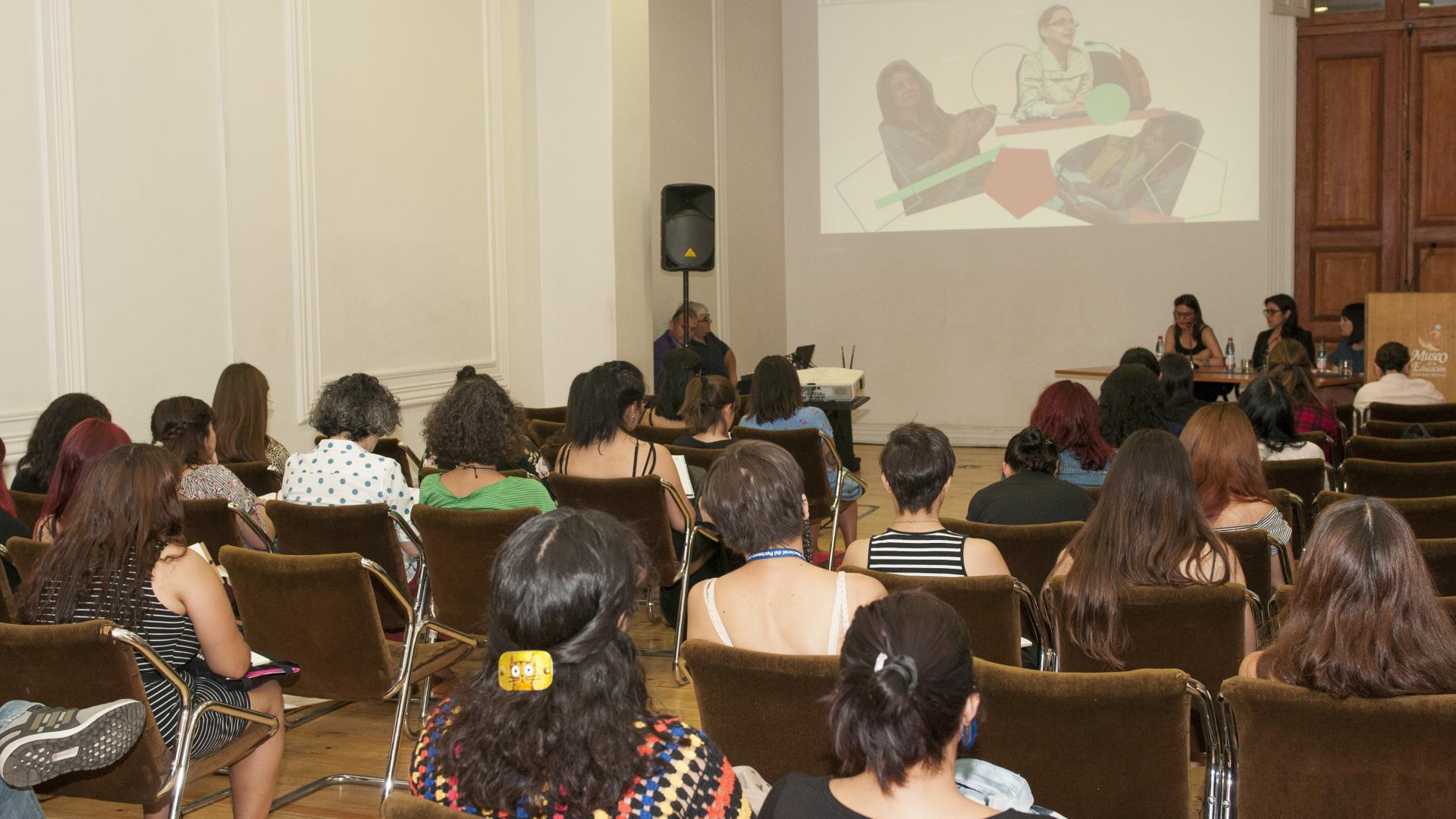 Imagen de un audiorio con un grupo de personas mirando una pantalla