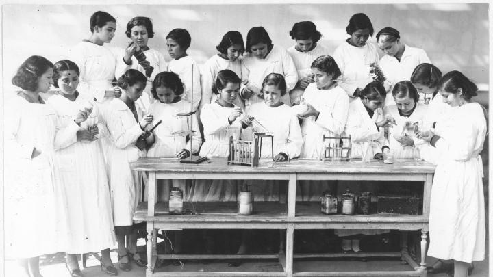 Foto en blanco y negro de un grupo de estudiantes utilizando herramientas de ciencias.
