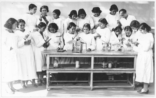 Foto en blanco y negro de un grupo de estudiantes utilizando herramientas de ciencias.