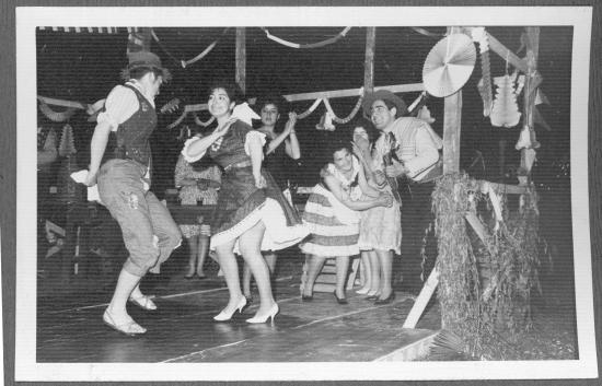Grupo de personas, hombres y mujeres, bailando cueca con trajes típicos y con instrumentos musicales